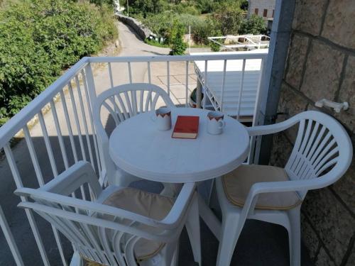 uma mesa e cadeiras com um livro na varanda em Apartments with a parking space Mocici, Dubrovnik - 12856 em Cilipi