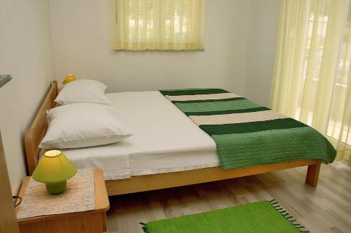um quarto com uma cama com um cobertor verde e branco em Apartments with a parking space Bilo, Primosten - 12870 em Primošten