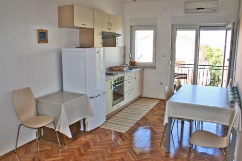 cocina con mesa y nevera blanca en Apartment Bilo 12868b en Primošten