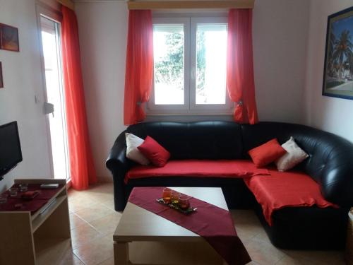 a living room with a black leather couch and red curtains at Apartments by the sea Seget Vranjica, Trogir - 12915 in Trogir