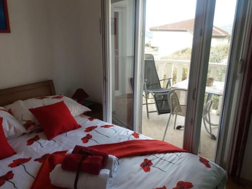 a bedroom with a bed with red pillows and a balcony at Apartments by the sea Seget Vranjica, Trogir - 12915 in Trogir