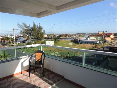 a chair on a balcony with a view of a street at Pousada Molhes da Barra in Torres