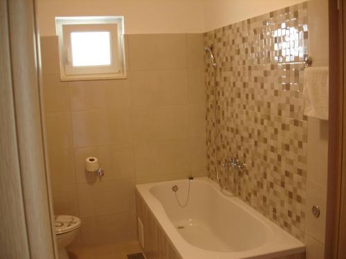 een badkamer met een bad, een toilet en een raam bij Apartments with a parking space Orebic, Peljesac - 12361 in Orebić