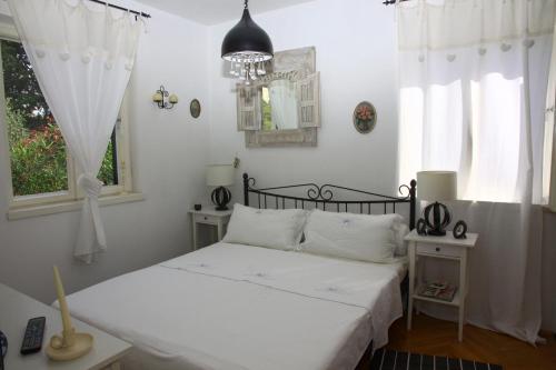 um quarto branco com uma cama e 2 janelas em Seaside holiday house Postira, Brac - 13001 em Postira
