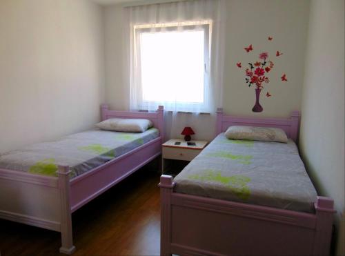 two beds in a small room with a window at Apartments with a parking space Liznjan, Medulin - 13009 in Ližnjan