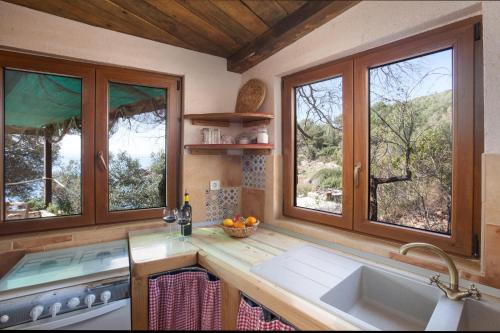 a kitchen with windows and a sink and a stove at Secluded fisherman's cottage Cove Tvrdni Dolac, Hvar - 13018 in Gdinj