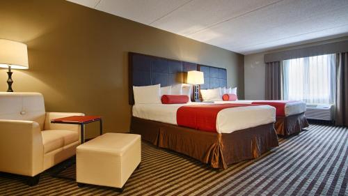 a hotel room with two beds and a chair at Comfort Inn & Suites Copley Akron in Copley