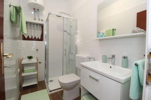 uma casa de banho branca com um WC e um chuveiro em Apartments and rooms with parking space Pag - 13060 em Pag