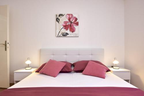 um quarto com uma cama branca e almofadas cor-de-rosa em Triple Room Trogir 13102b em Trogir