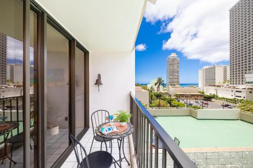 a balcony with a table and chairs and a view of the city at Remodeled 1BR Condo, Steps to Beach, Free Parking! in Honolulu