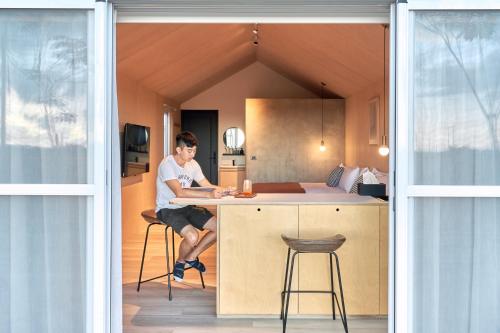 a man sitting at a kitchen counter in a tiny house at Sun Wild BnB in Sanxing