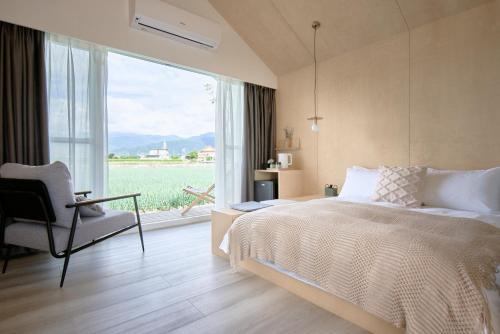 sypialnia z łóżkiem, krzesłem i oknem w obiekcie Sun Wild BnB w mieście Sanxing