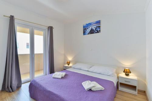 een slaapkamer met een paars bed en een groot raam bij Apartments by the sea Nin, Zadar - 13172 in Nin