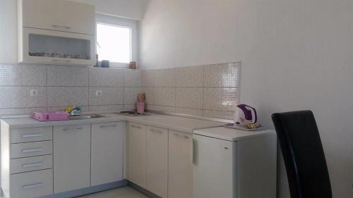 a white kitchen with white cabinets and a window at Apartments by the sea Gradac, Makarska - 13181 in Gradac