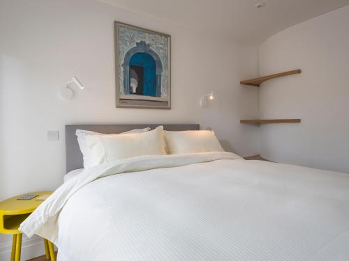 1 dormitorio con cama blanca y mesa amarilla en The Bothy en Slapton