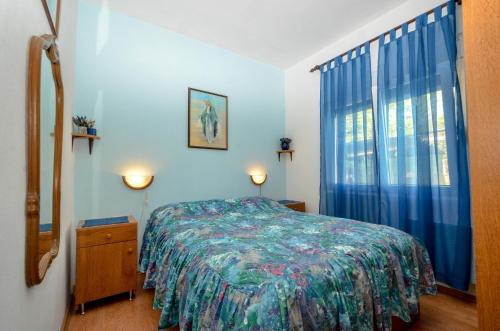 een slaapkamer met een bed en een raam met blauwe gordijnen bij Apartments by the sea Guduce, Ugljan - 13274 in Ugljan