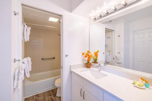 a bathroom with a sink and a toilet and a mirror at Beautiful Ocean and Diamond Head Views with Parking in Honolulu