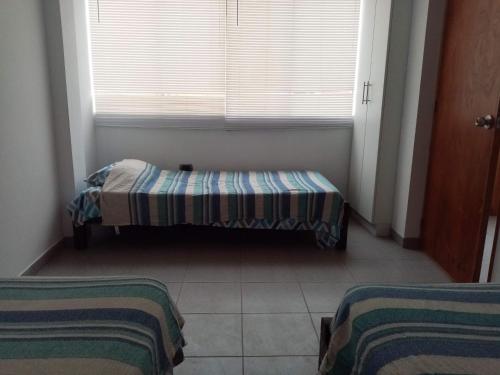 a small room with a bed and a window at Departamentos Cerro Azul P2 in Cerro Azul