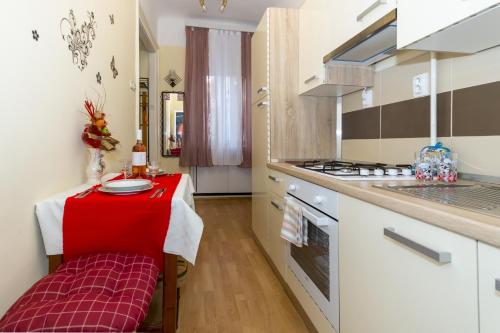 a kitchen with a table with a red cloth on it at Apartments by the sea Rijeka - 13293 in Rijeka