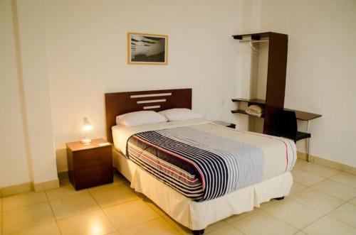 a bedroom with a large bed and a night stand at Hostal Oro Negro in Talara