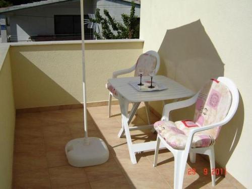 a small table with two chairs and an umbrella at Apartments by the sea Brgulje, Molat - 13318 in Molat