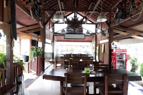 um restaurante vazio com mesas e cadeiras de madeira em Pondok Kelapa Homestay Lampung Mitra RedDoorz em Bandar Lampung