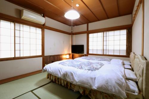 a bedroom with a bed in a room with windows at Villa Izumoya in Izumo