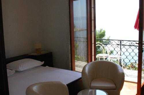 a bedroom with a bed and two chairs and a balcony at Double Room Puntinak 12255a in Selca