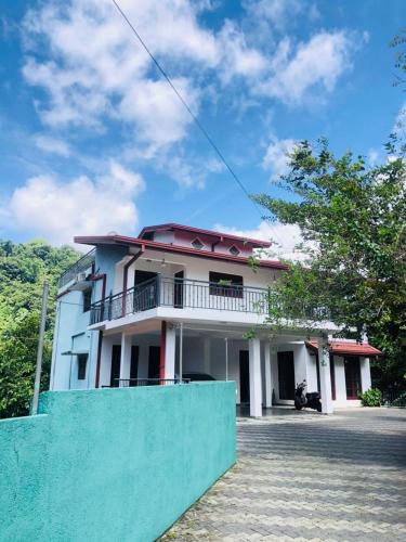 una casa con una valla azul delante de ella en Sun Set Forest Villa, en Kandy