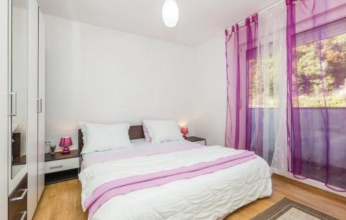 a white bedroom with a large bed with purple curtains at Apartments with a parking space Kastav, Opatija - 13457 in Kastav