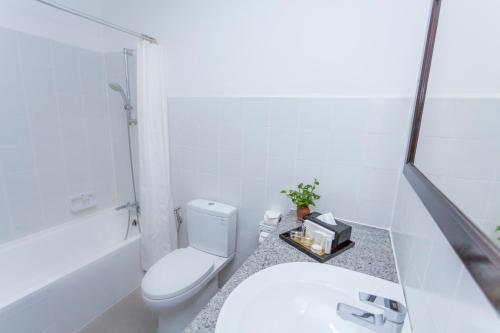 a white bathroom with a toilet and a sink at Le Charme Vientiane Hotel in Vientiane