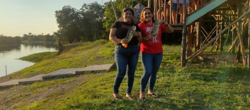 two women standing next to a river with a turtle at Casa Kukama Lodge in Iquitos