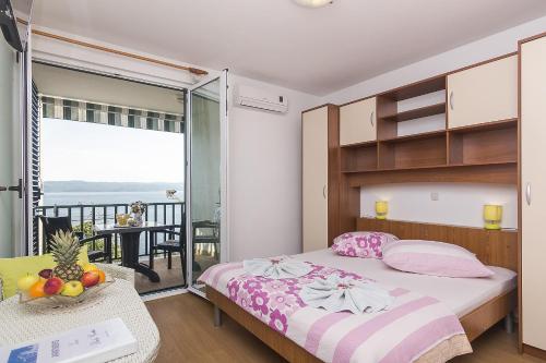 a bedroom with a bed and a balcony with a table at Apartments with a parking space Brela, Makarska - 11687 in Brela