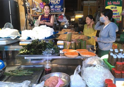 a group of people standing in a market with food at Giao Hòa Homestay Hội An in Hoi An