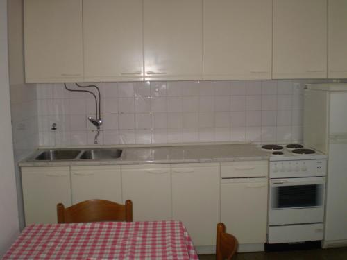 una cucina con mobili bianchi, un lavandino e un tavolo di Apartments by the sea Bol, Brac - 13539 a Bol