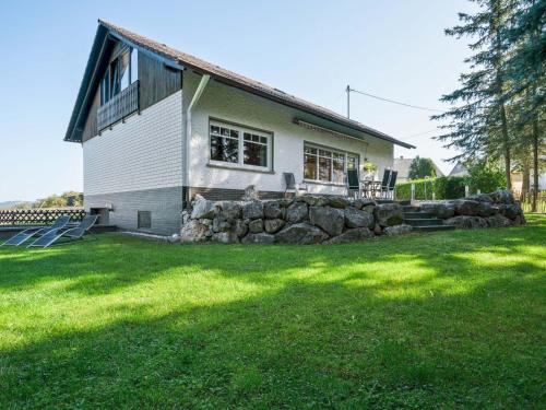 A detached holiday home in a highly scenic area في Trierscheid: منزل به جدار صخري أمام ساحة
