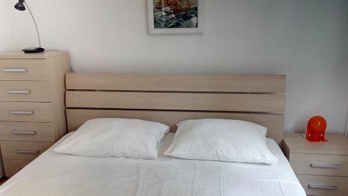 ein Bett mit zwei weißen Kissen und einem Kopfteil aus Holz in der Unterkunft Apartments by the sea Mali Losinj (Losinj) - 13556 in Veli Lošinj