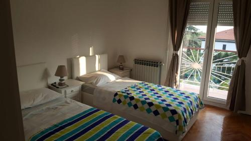 a bedroom with two beds and a large window at Apartments with a parking space Kostrena, Rijeka - 13563 in Kostrena