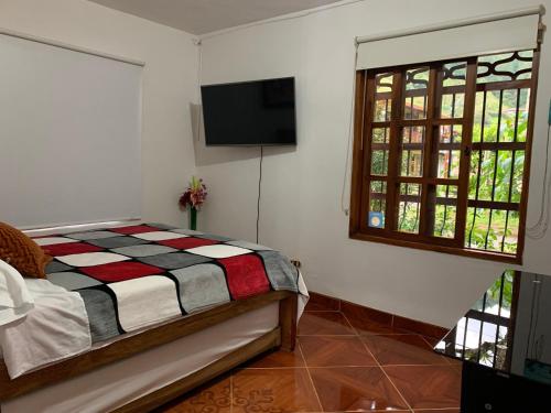 a bedroom with a bed and a flat screen tv at Casa Huespedes EL ENSUEÑO in Jardin