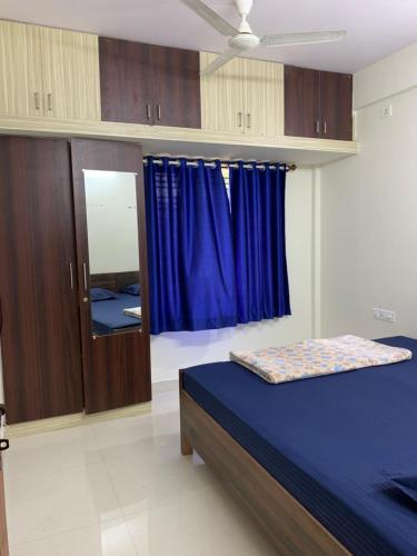 een slaapkamer met een blauw bed en een spiegel bij Haven Homes in Yelahanka
