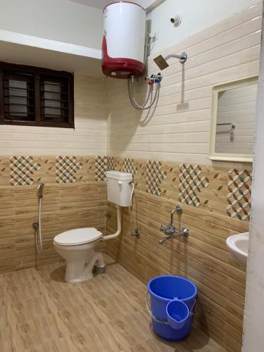 een badkamer met een toilet, een wastafel en een emmer bij Haven Homes in Yelahanka