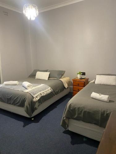 a bedroom with two beds and a chandelier at Bank Hotel Dungog in Dungog