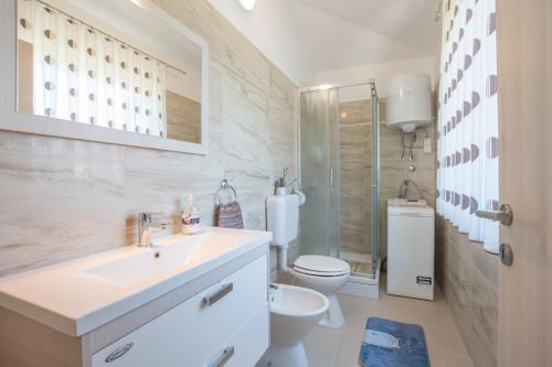a white bathroom with a toilet and a sink at Holiday house with a parking space Kastel, Central Istria - Sredisnja Istra - 14572 in Buje