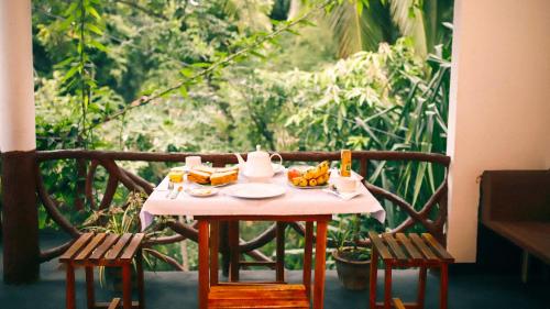 einen Tisch mit Essen drauf mit zwei Stühlen in der Unterkunft Aloe Vera Guest House in Dambulla