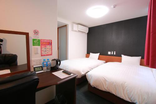Habitación de hotel con 2 camas y escritorio en iyashi no yado isshinkan, en Kanoya