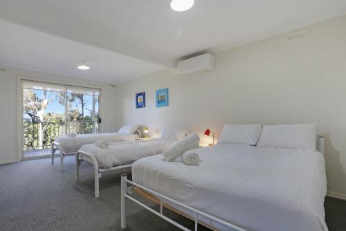 a bedroom with three beds and a window at LAKESIDE2 in Merimbula