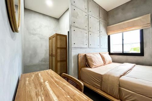 a small bedroom with a bed and a table at Rattanhaus R Signature Mitra RedDoorz in Palembang