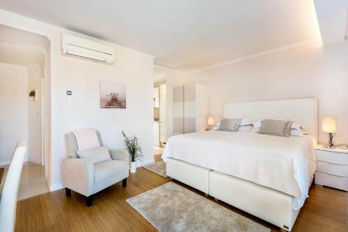 a white bedroom with a bed and a chair at Apartments and rooms with WiFi Zagreb - 14675 in Zagreb