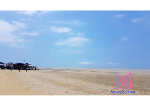 a beach with a pier and a pink sign on it at Gold Coast Morib Resort in Banting