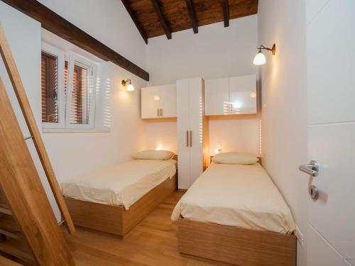 two beds in a room with white walls and wooden floors at Holiday house with a swimming pool Preko, Ugljan - 14707 in Preko